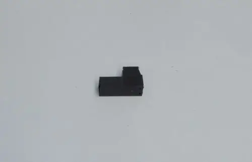 Schwarzer Stecker mit einer L-förmigen Struktur, liegend auf einem hellen Untergrund. Das Produkt gehört zur Marke Daikin.